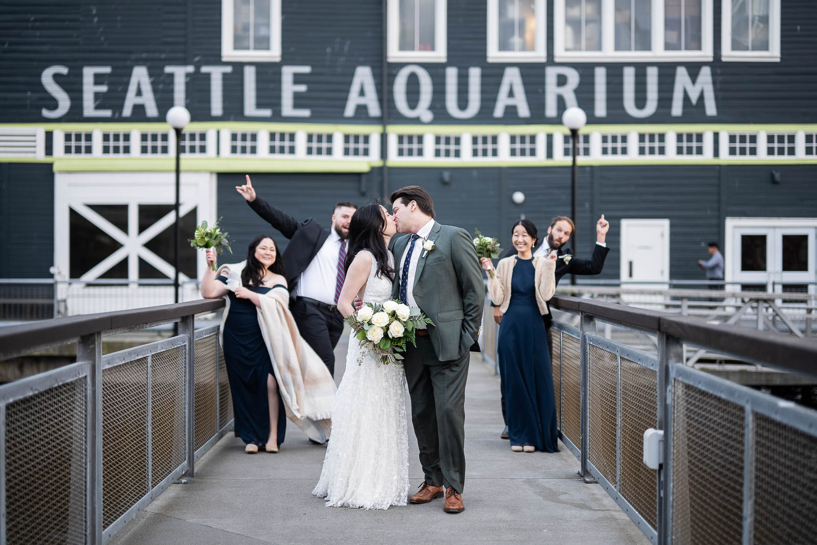 couple poses in front of Seattle aquarium on wedding day